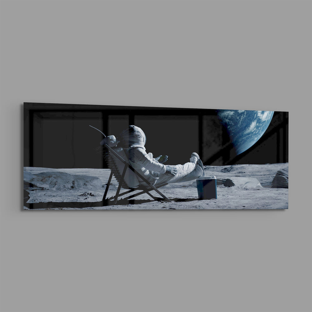 A spacesuited astronaut lounging in a deck chair on the lunar surface while planet Earth hangs in the black sky. panoramic glass wall art E