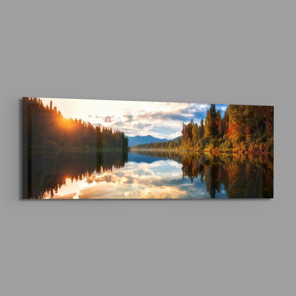 A mirror-calm lake at sunrise reflecting autumn forest, distant mountains, and a glowing cloudy sky. panoramic glass wall art E