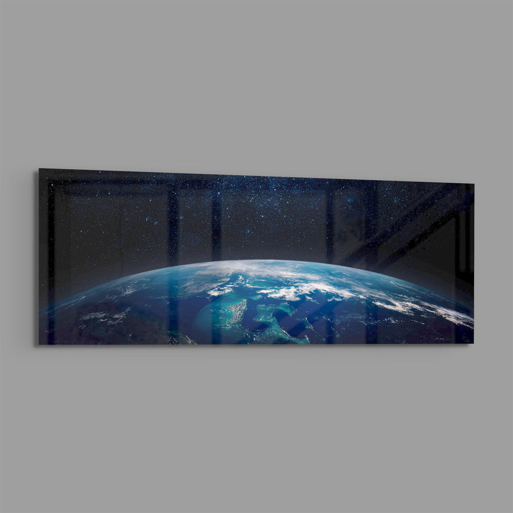 The curved edge of planet Earth seen from orbit, blue oceans and swirling clouds under a starry black sky. panoramic glass wall art E
