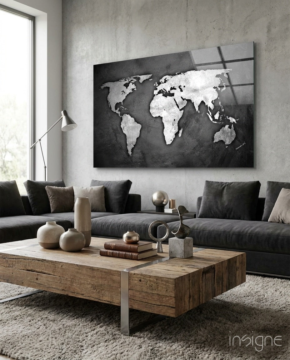 Grunge World Map glass wall art displayed above a charcoal sectional in a light concrete-walled lounge