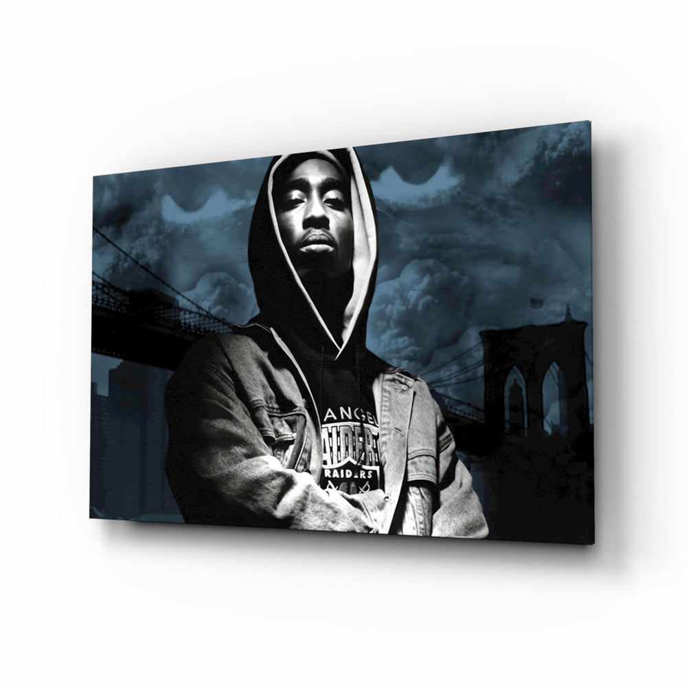 Tupac Shakur glass wall art displayed above a black leather sectional in a moody music room with reclaimed-wood console and brass arc lamp