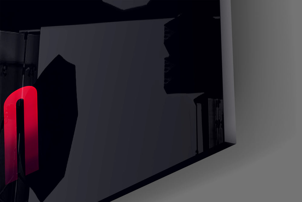 Close-up detail of the elongated scarlet letterforms on navy behind glass