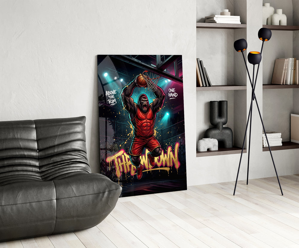 gorilla basketball player dunking one-handed glass wall art leaning beside a dark leather sofa