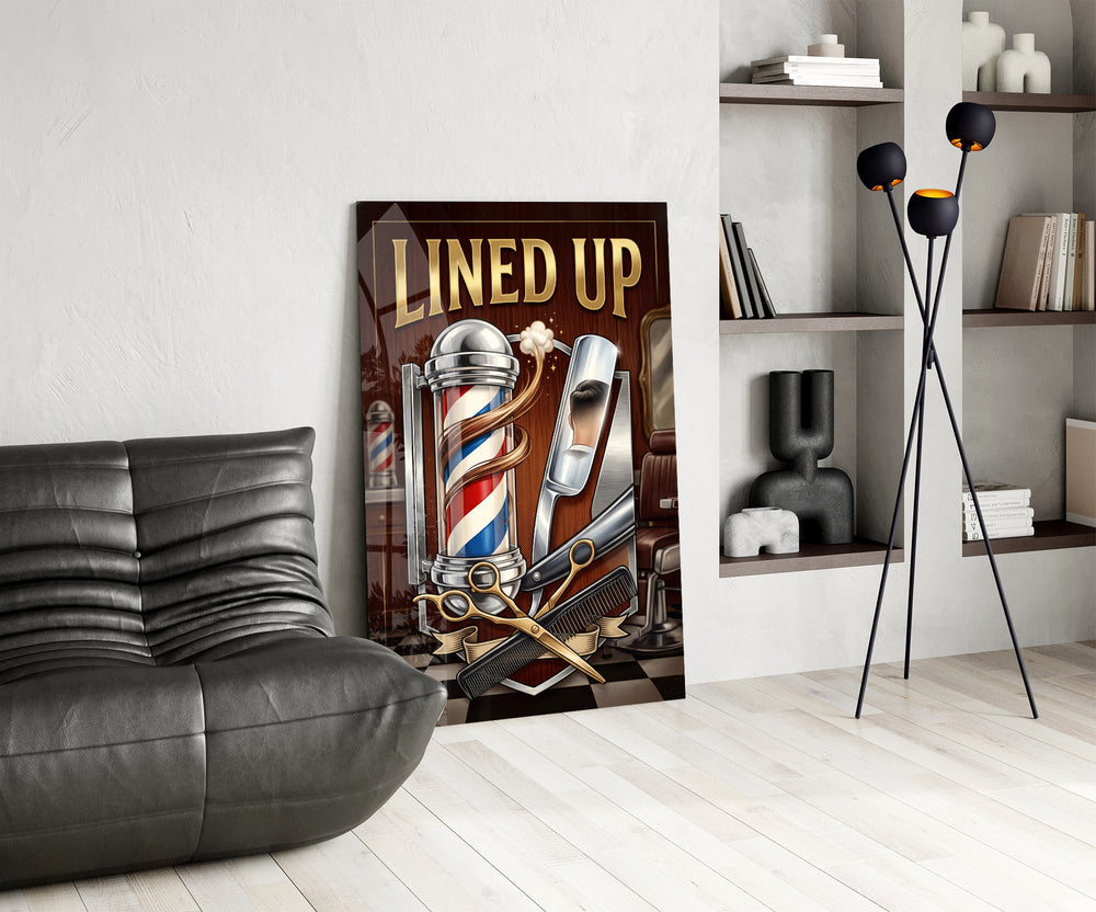 lined up vintage barbershop emblem glass wall art leaning beside a dark leather sofa