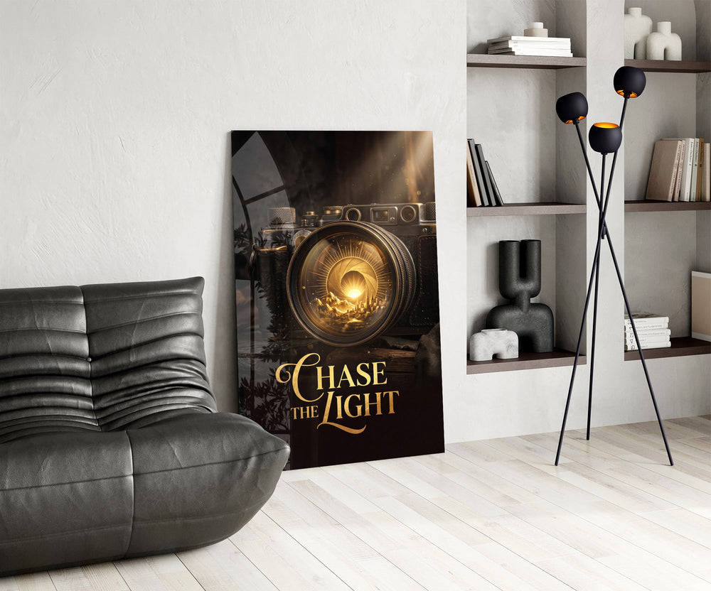 gold vintage camera with a sunrise lens glass wall art leaning beside a dark leather sofa