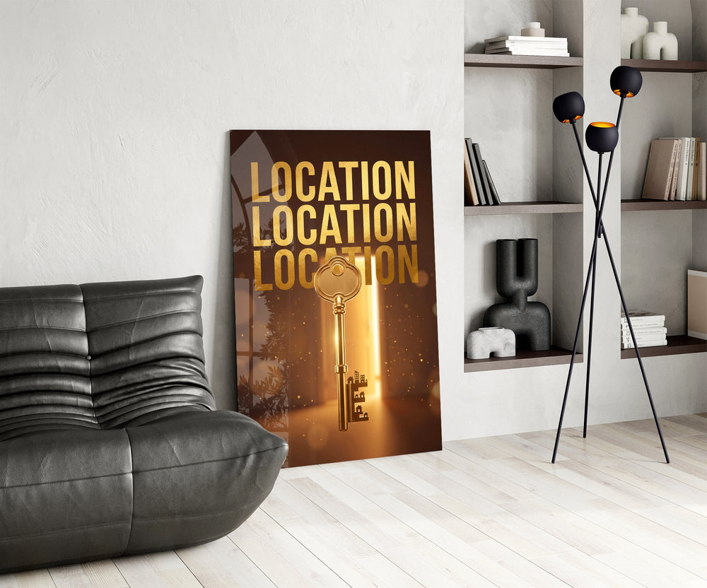 gold real estate key with a skyline glass wall art leaning beside a dark leather sofa