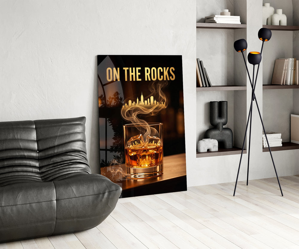 whiskey glass with a golden skyline glass wall art leaning beside a dark leather sofa