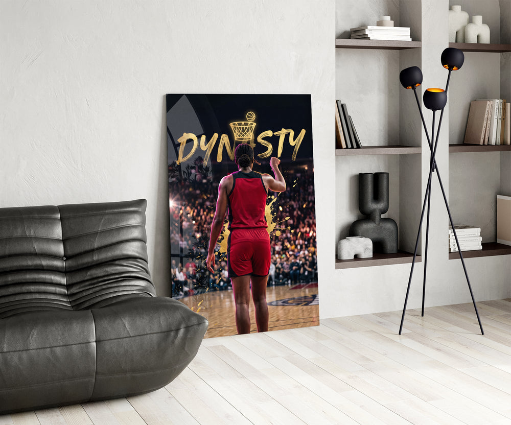 gold Dynasty basketball typography glass wall art leaning beside a dark leather sofa