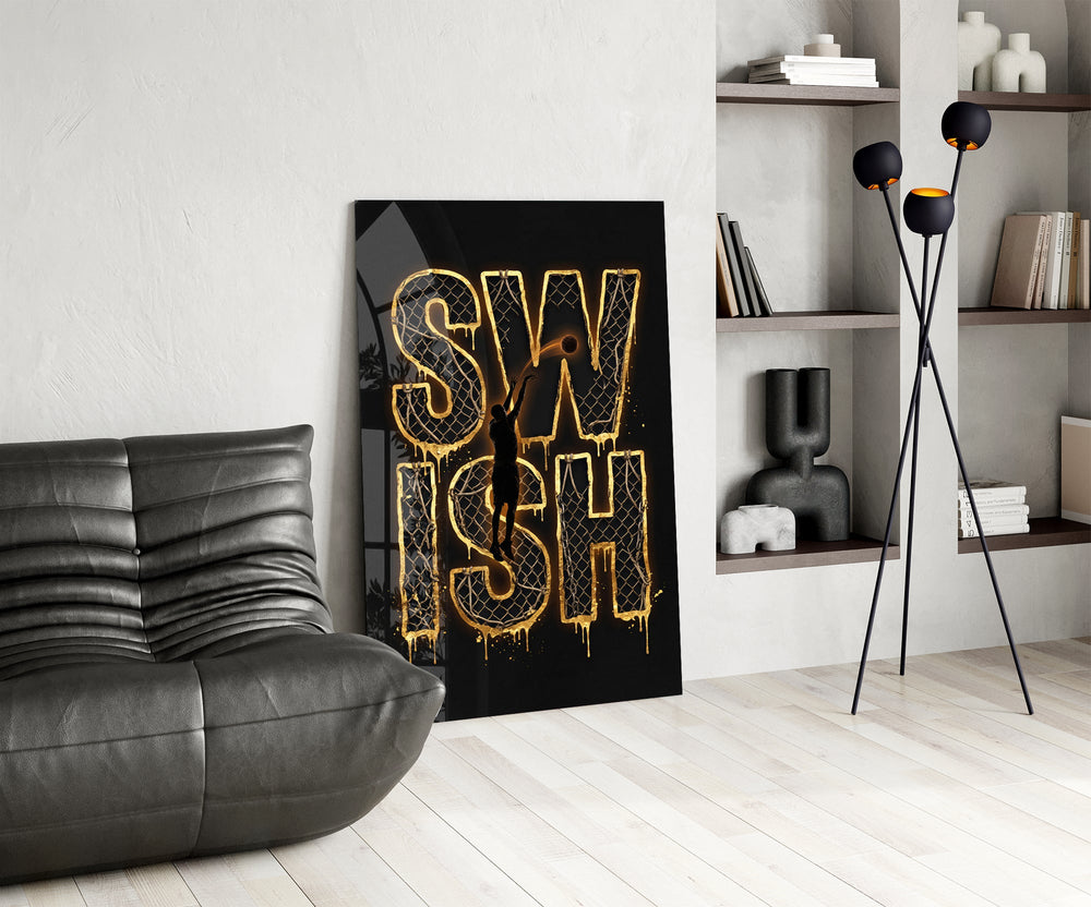 gold Swish basketball typography glass wall art leaning beside a dark leather sofa