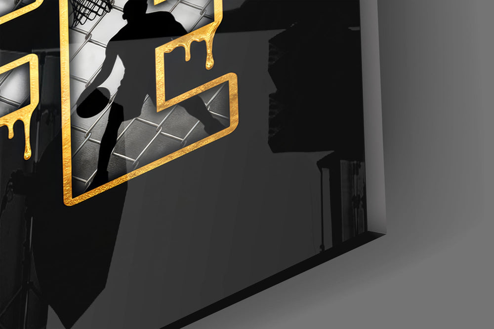 Close-up detail of the player silhouettes and hoops set inside the dripping gold letters on the glass surface