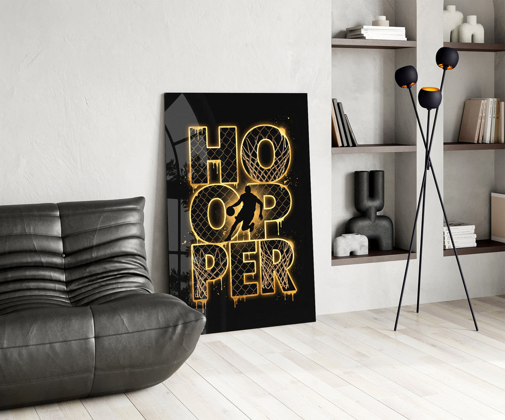 gold basketball typography with a dribbling silhouette glass wall art leaning beside a dark leather sofa