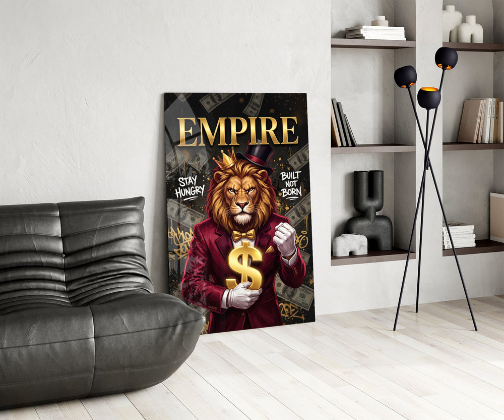 a crowned lion in a red suit holding a gold dollar sign glass wall art leaning beside a dark leather sofa
