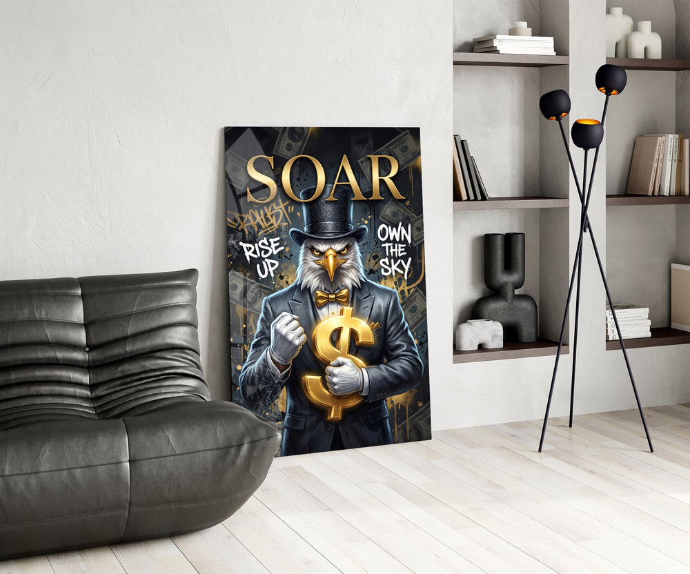 suited bald eagle holding a gold dollar sign glass wall art leaning beside a dark leather sofa