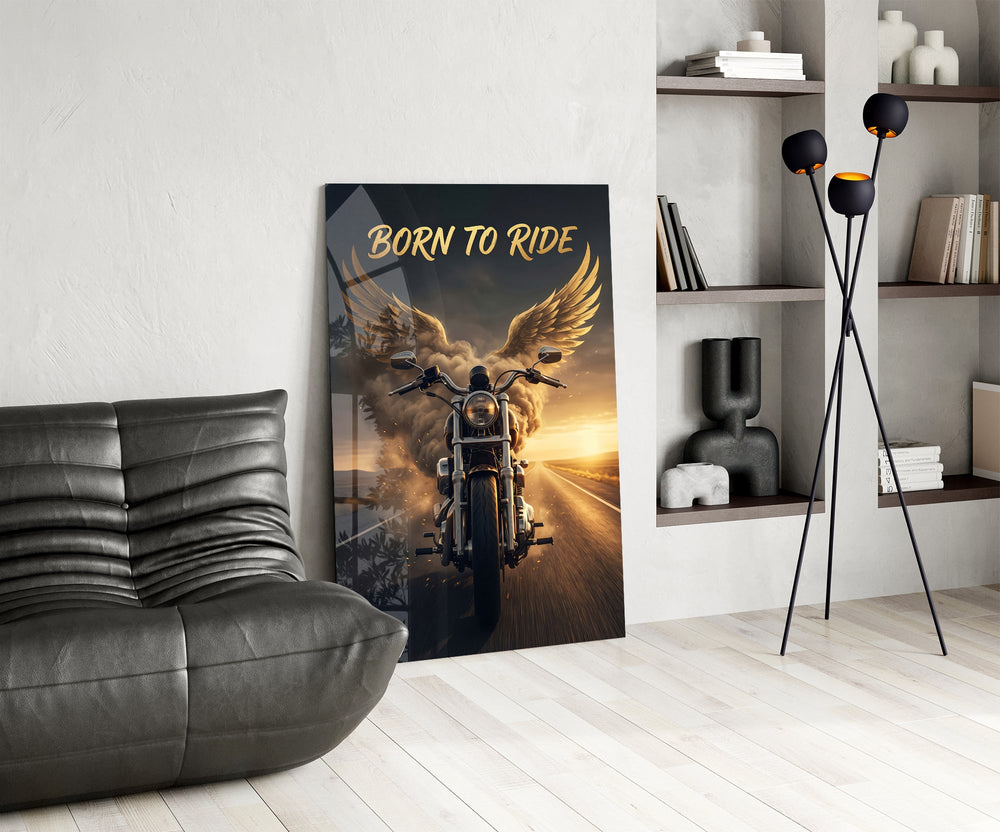 born to ride winged motorcycle glass wall art leaning beside a dark leather sofa