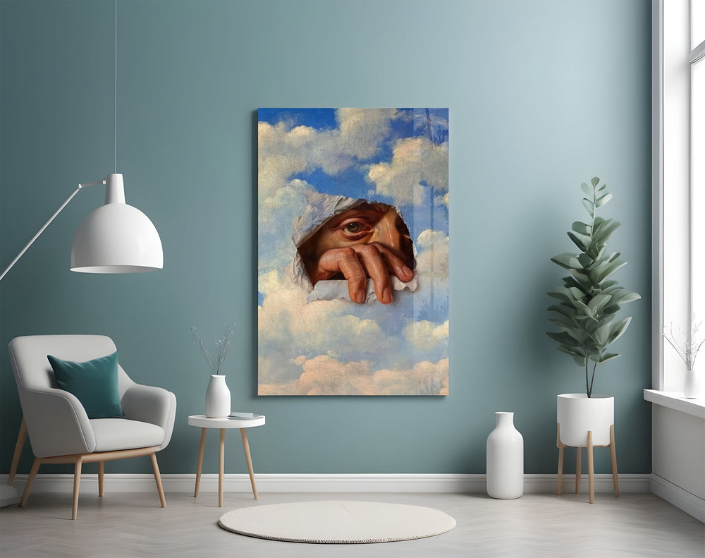 an eye and hand breaking through a painted sky glass wall art styled above an armchair in a reading corner