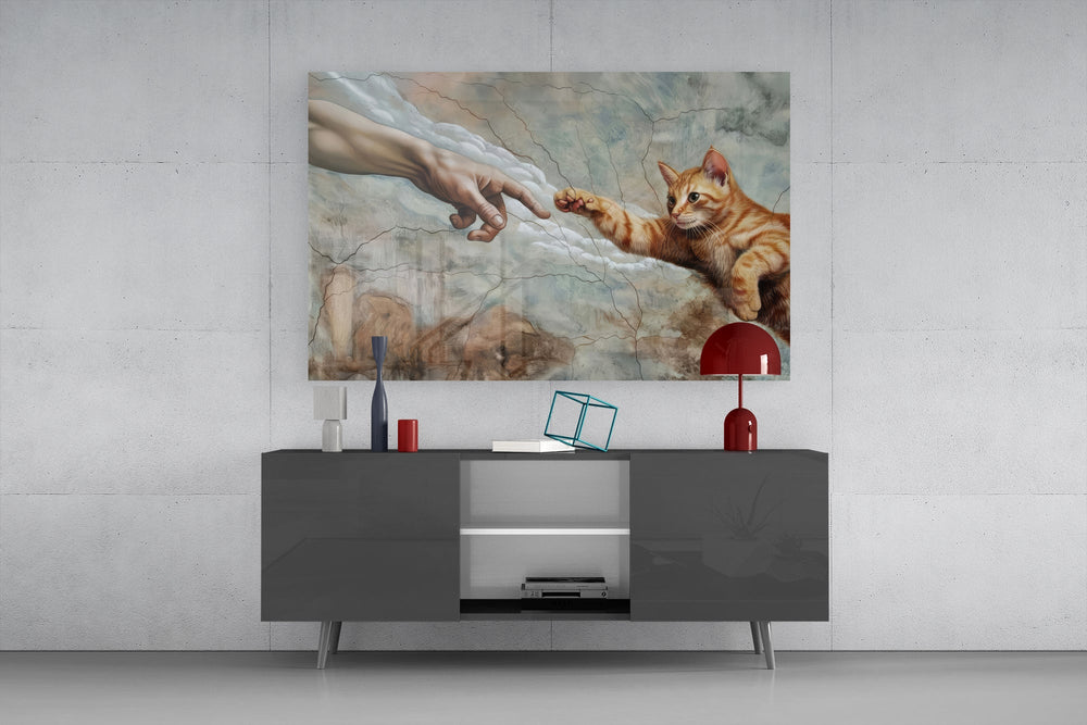 ginger kitten reaching a paw to a human hand glass wall art displayed above a console in a designer interior