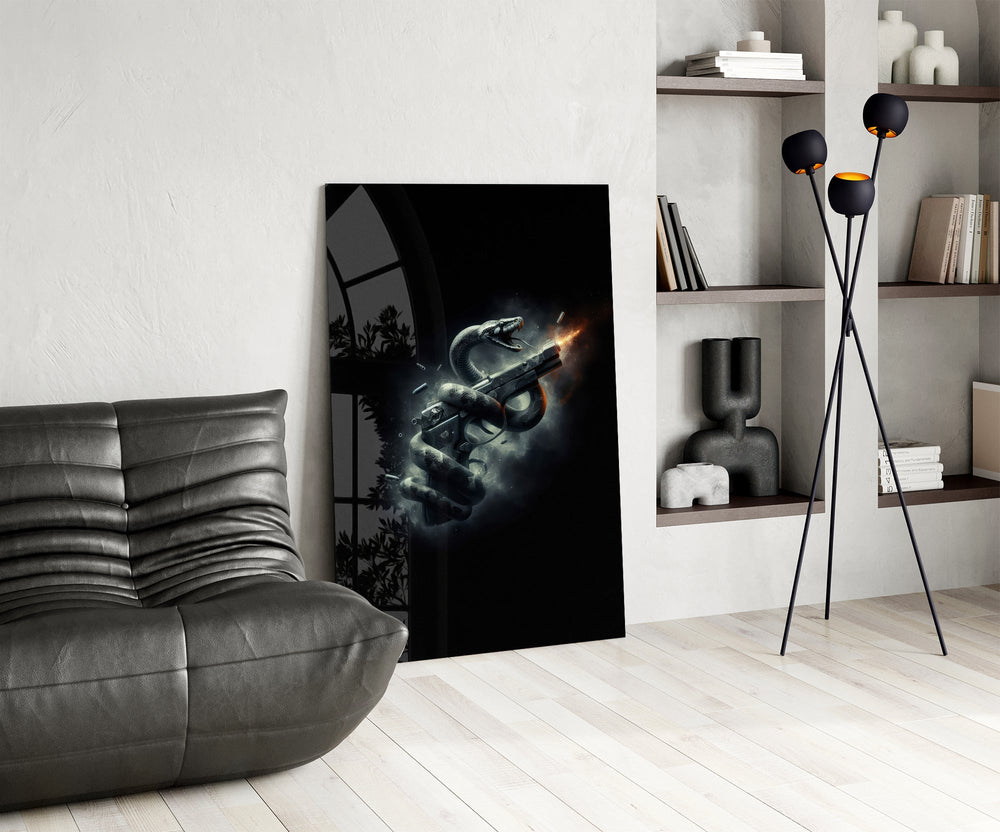 a serpent coiled around a firing pistol glass wall art leaning beside a dark leather sofa