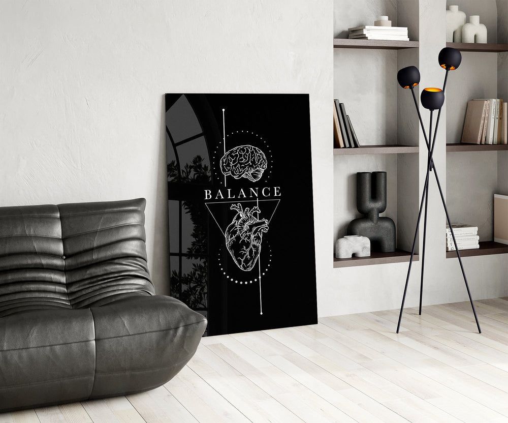 brain above heart balance on black glass wall art leaning beside a dark leather sofa