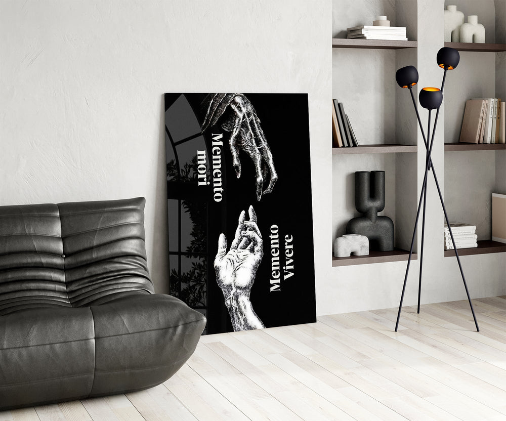 skeletal and living hands memento mori glass wall art leaning beside a dark leather sofa