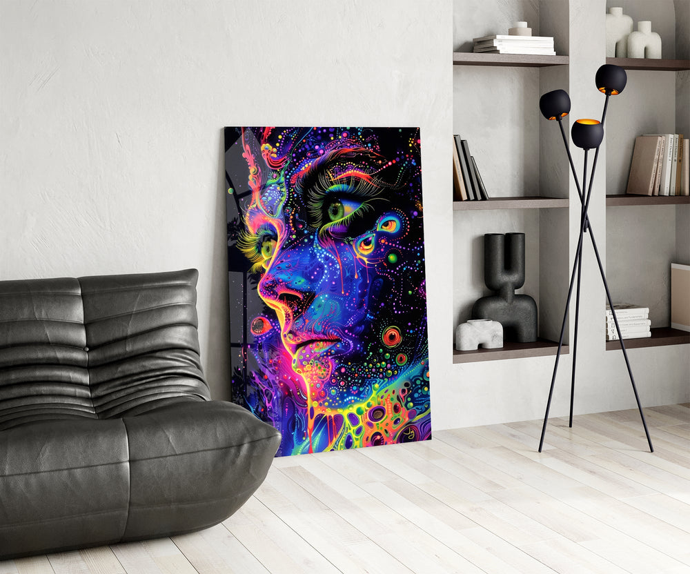 neon dot psychedelic woman's face glass wall art leaning beside a dark leather sofa