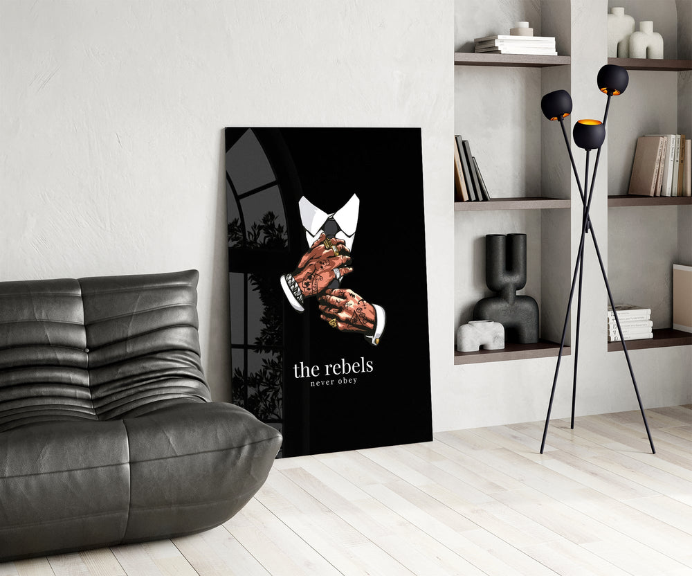 tattooed hands and the words the rebels never obey glass wall art leaning beside a dark leather sofa