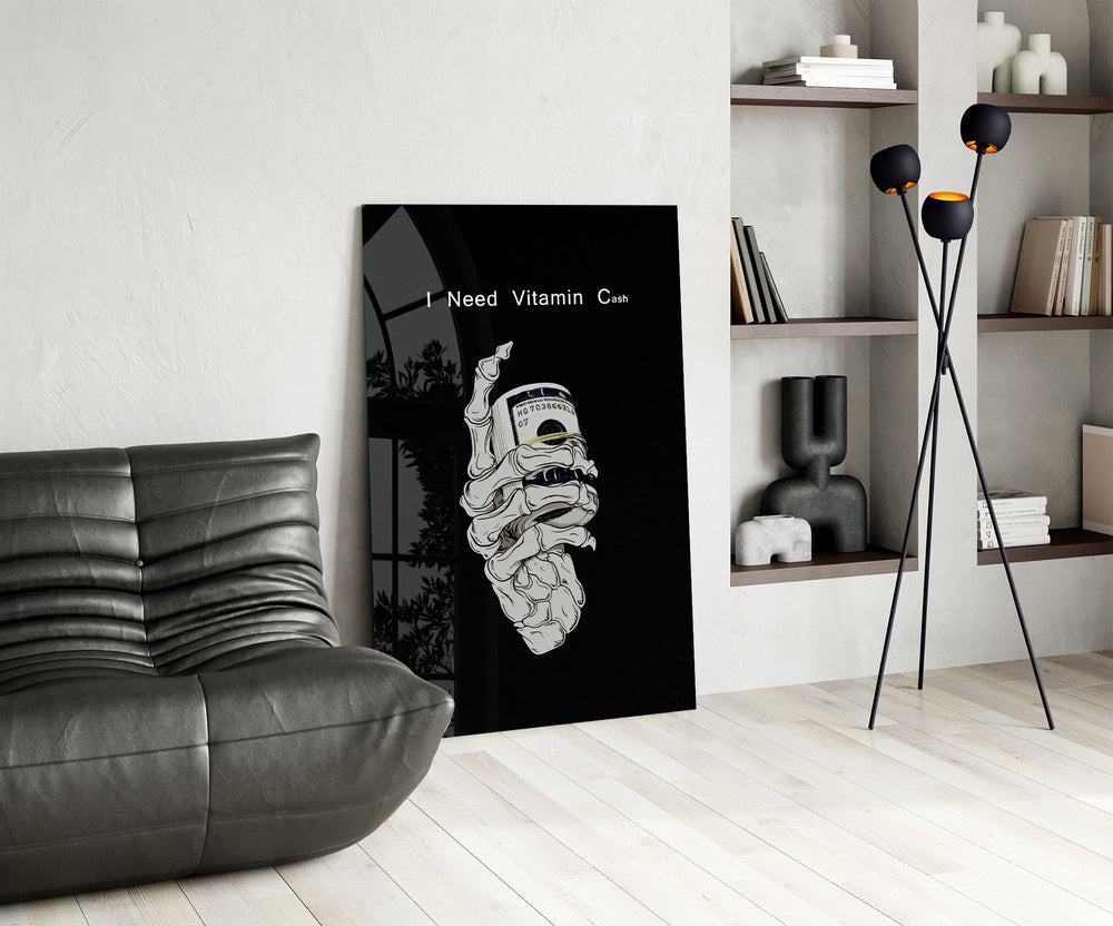 a skeleton hand gripping a roll of cash glass wall art leaning beside a dark leather sofa
