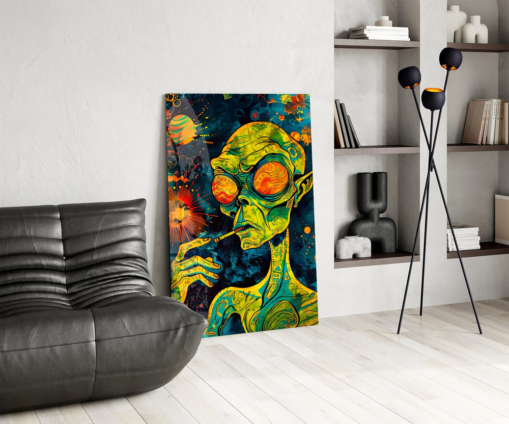 green alien smoking in deep space glass wall art leaning beside a dark leather sofa
