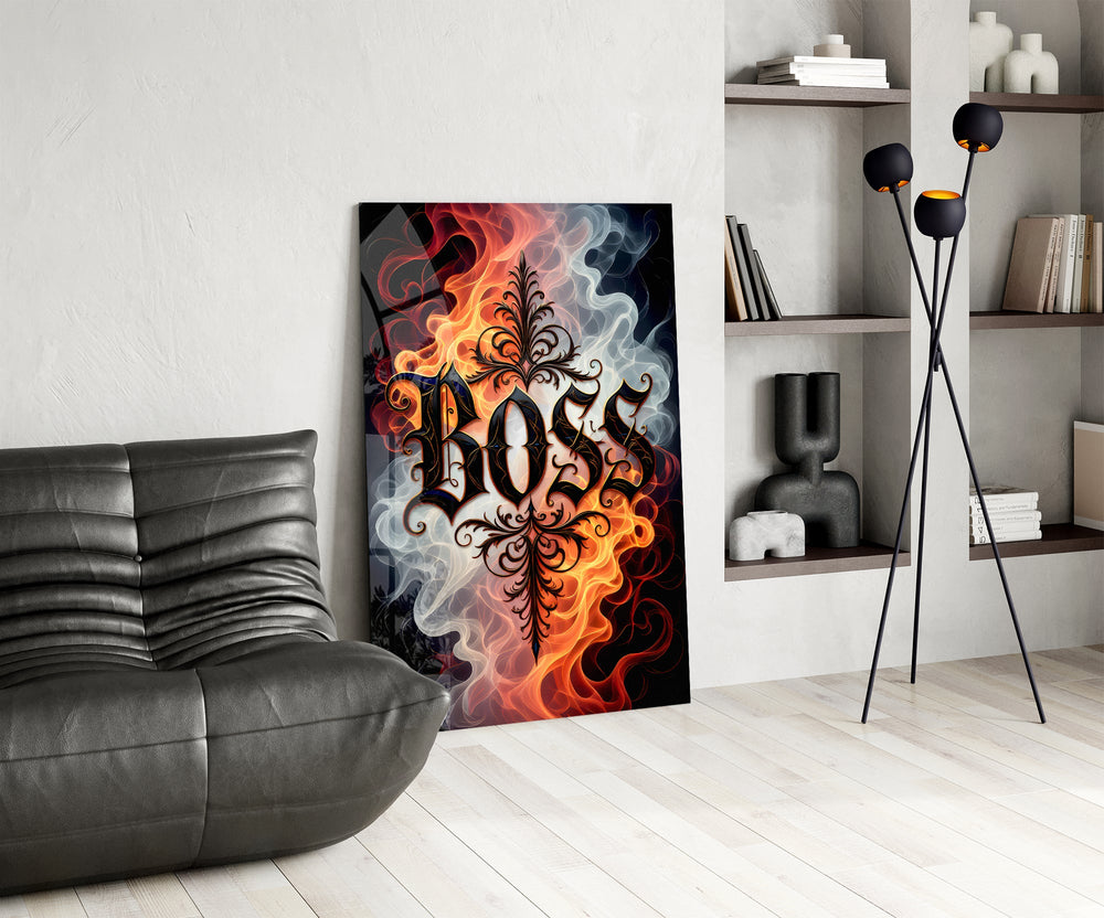 blackletter word in fire and smoke glass wall art leaning beside a dark leather sofa