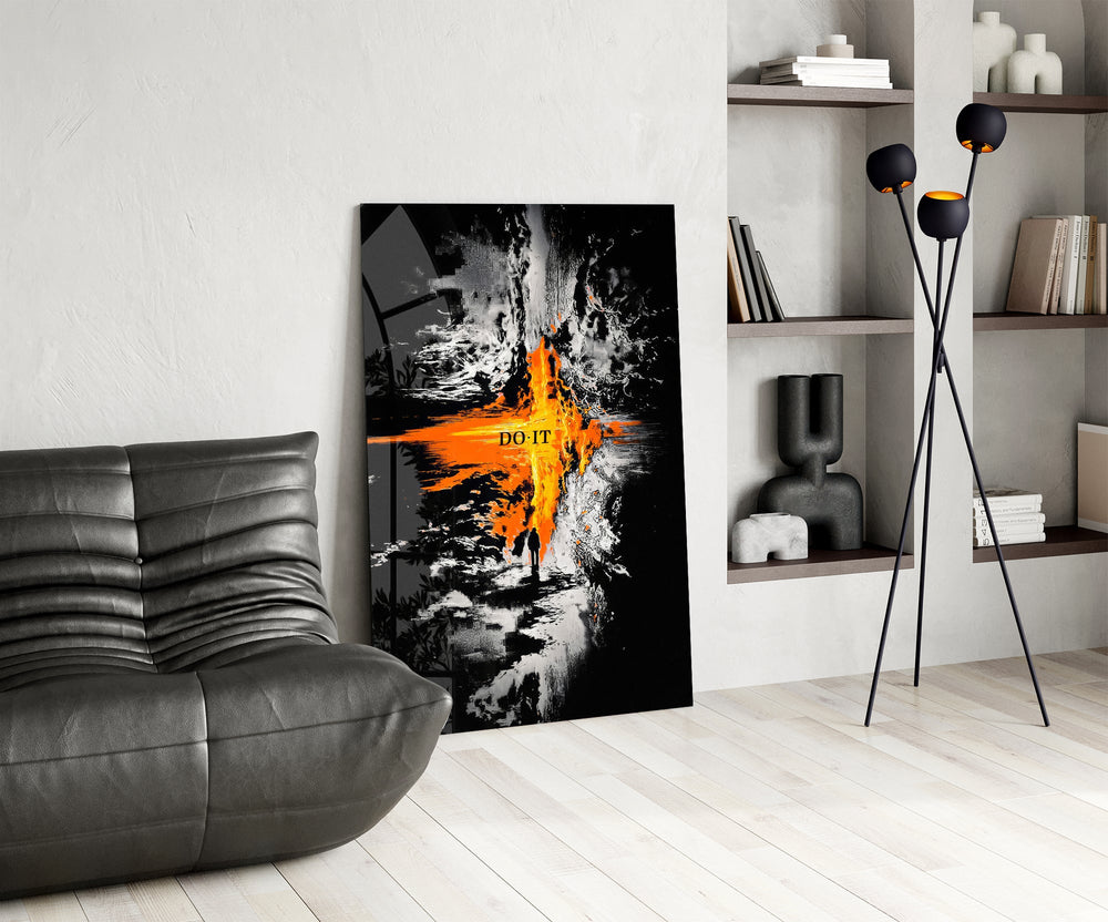 orange lava rift and lone figure glass wall art leaning beside a dark leather sofa