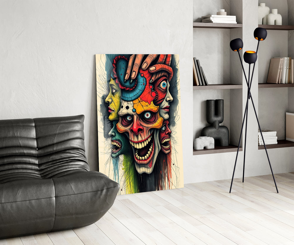 layered faces around a screaming skull glass wall art leaning beside a dark leather sofa