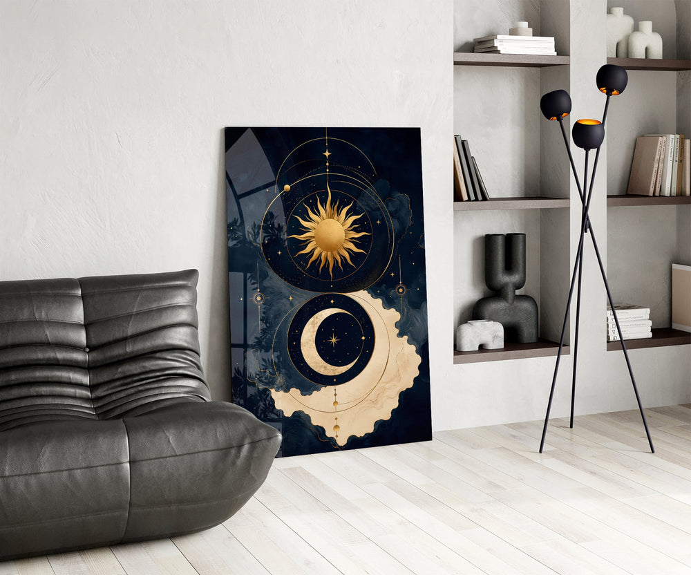 a gold sun and crescent moon on navy glass wall art leaning beside a dark leather sofa