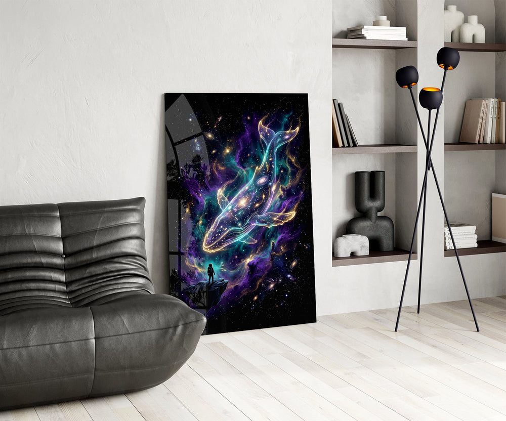 a galaxy-filled whale swimming through a nebula glass wall art leaning beside a dark leather sofa