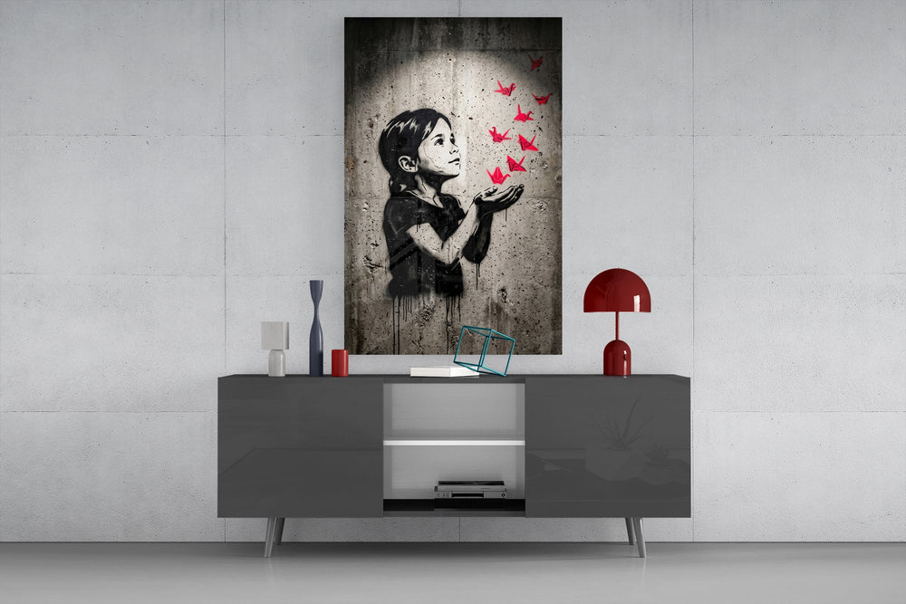 stencil girl releasing red paper cranes glass wall art displayed above a console in a designer interior