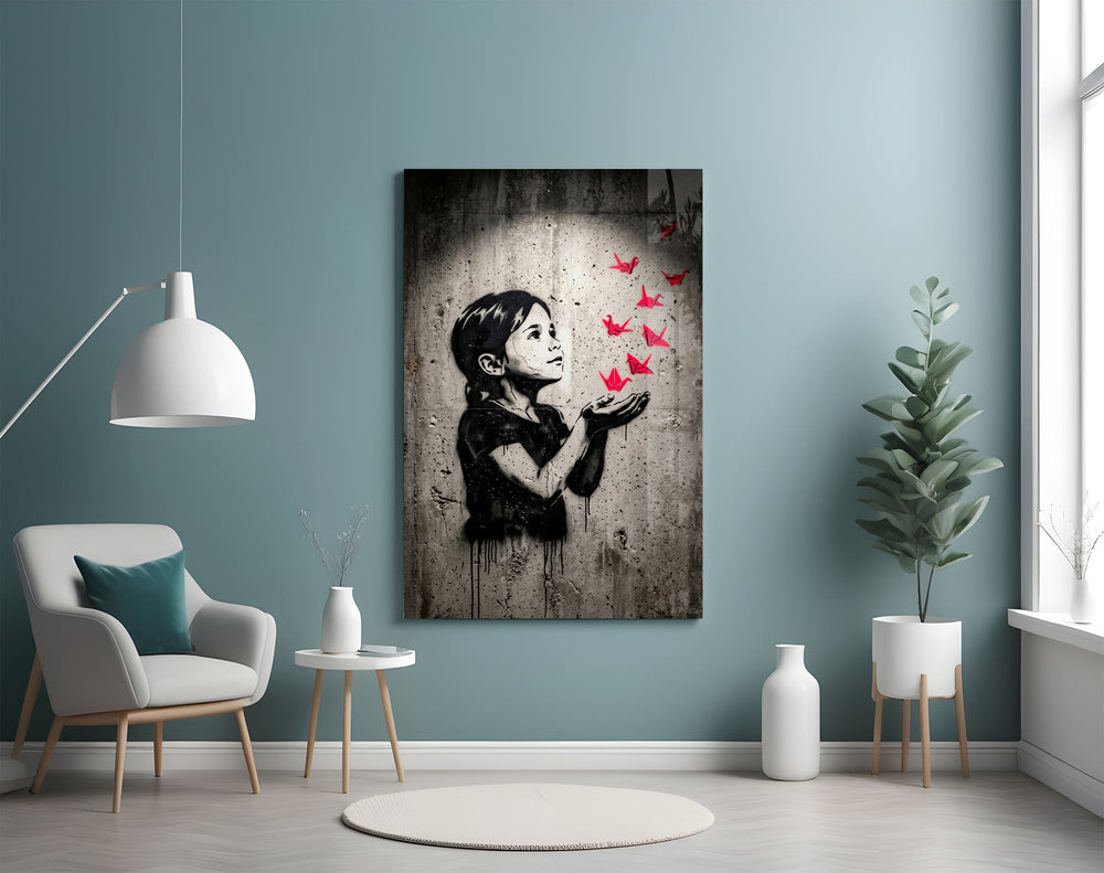 stencil girl releasing red paper cranes glass wall art styled above an armchair in a reading corner