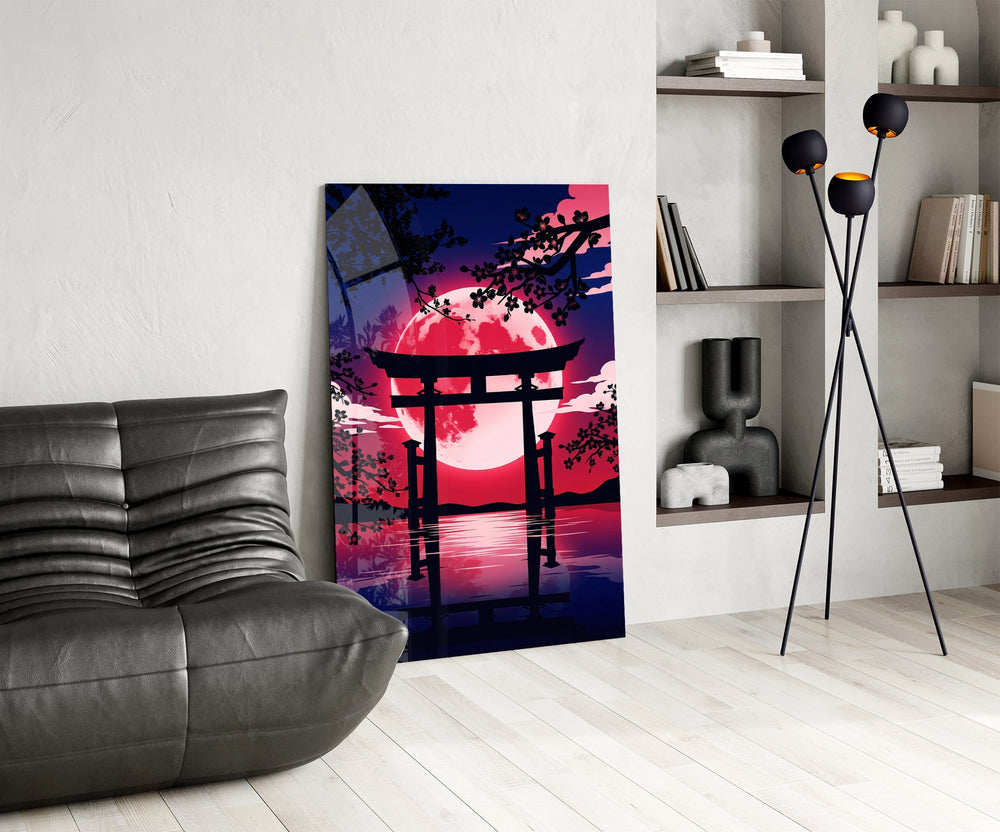 a torii gate before a crimson moon glass wall art leaning beside a dark leather sofa