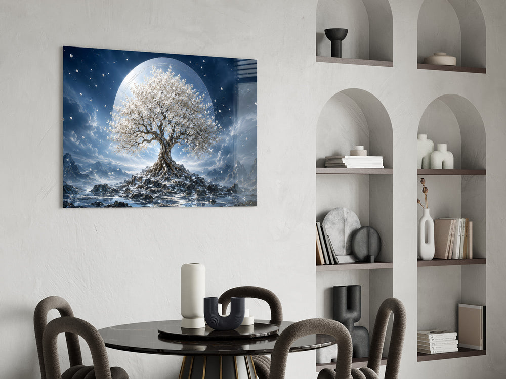 a white blossom tree beneath a full moon glass wall art leaning beside a dark leather sofa