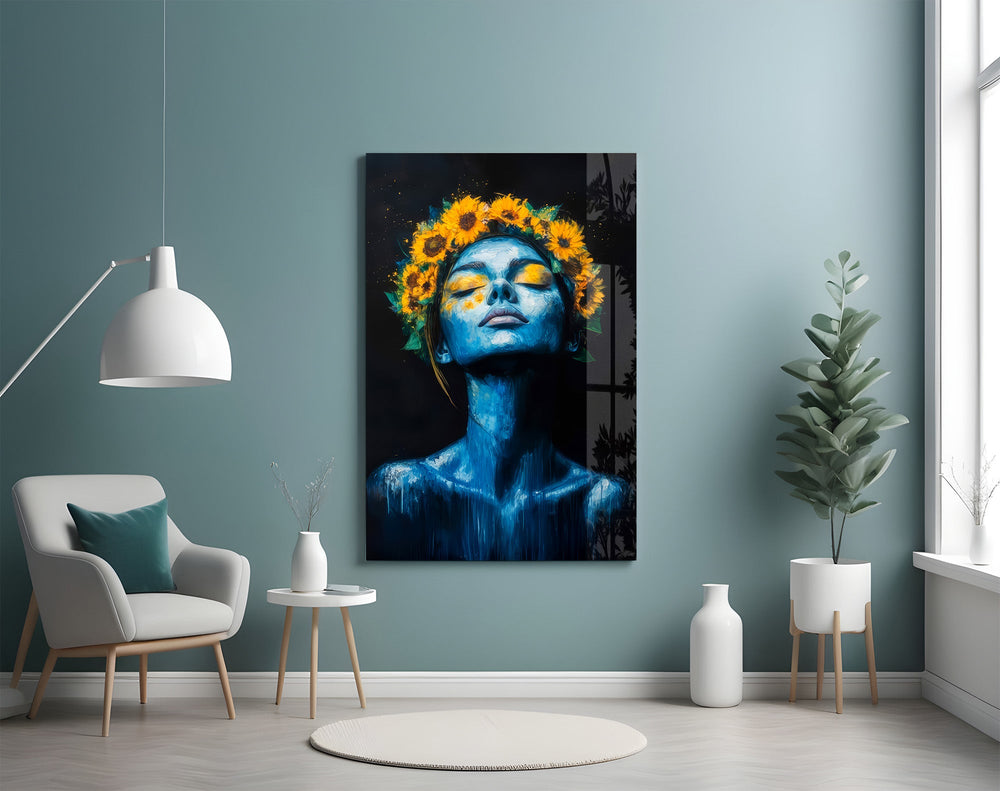 a blue-skinned woman crowned with sunflowers glass wall art styled above an armchair in a reading corner