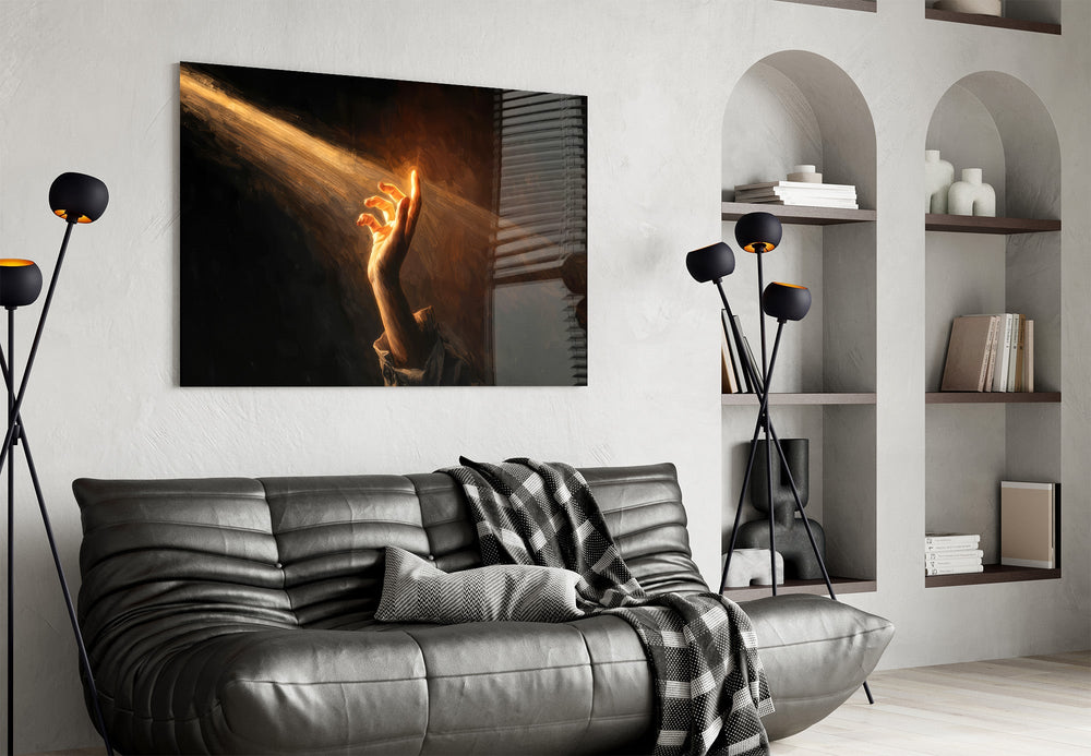 a hand reaching into a golden light beam glass wall art styled above an armchair in a reading corner