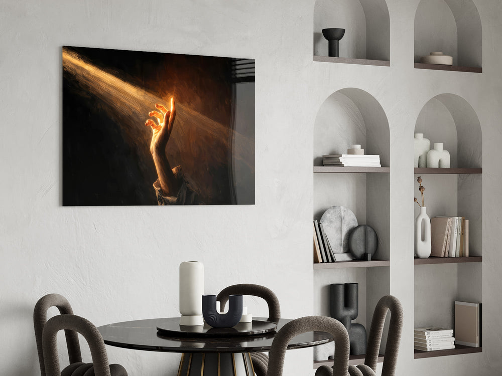 a hand reaching into a golden light beam glass wall art leaning beside a dark leather sofa