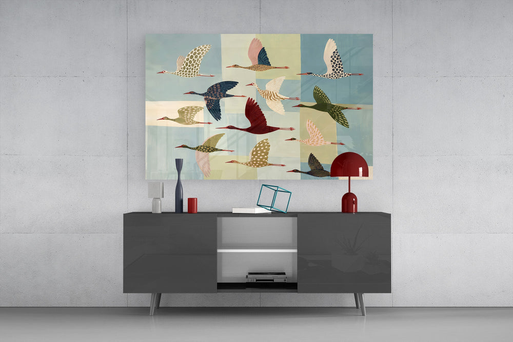 a flock of stylized cranes in flight glass wall art styled in an atmospheric room setting