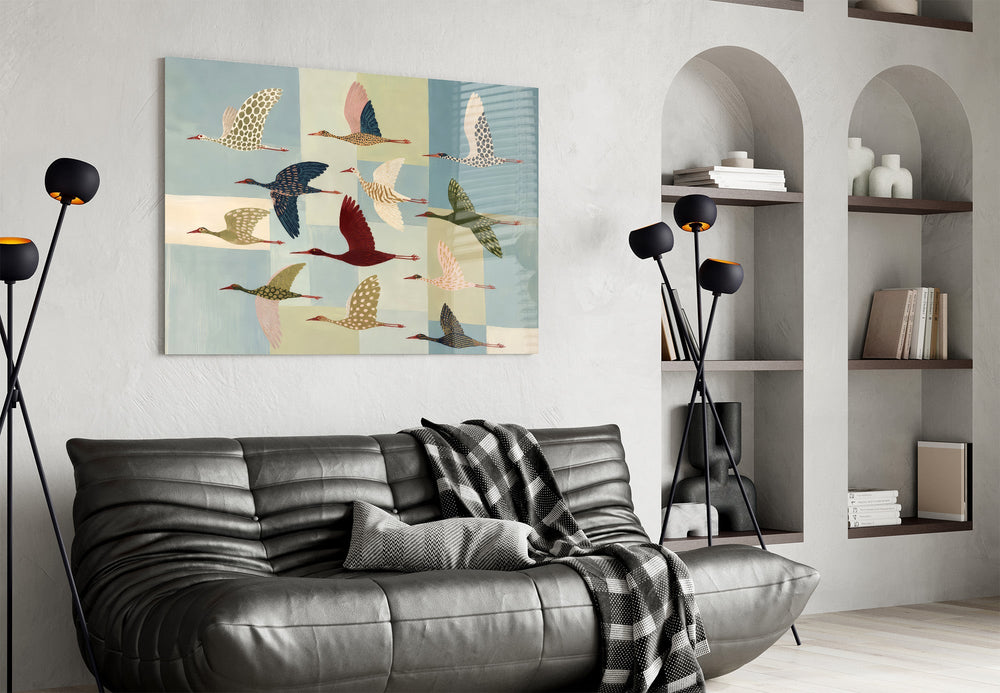 a flock of stylized cranes in flight glass wall art styled above an armchair in a reading corner