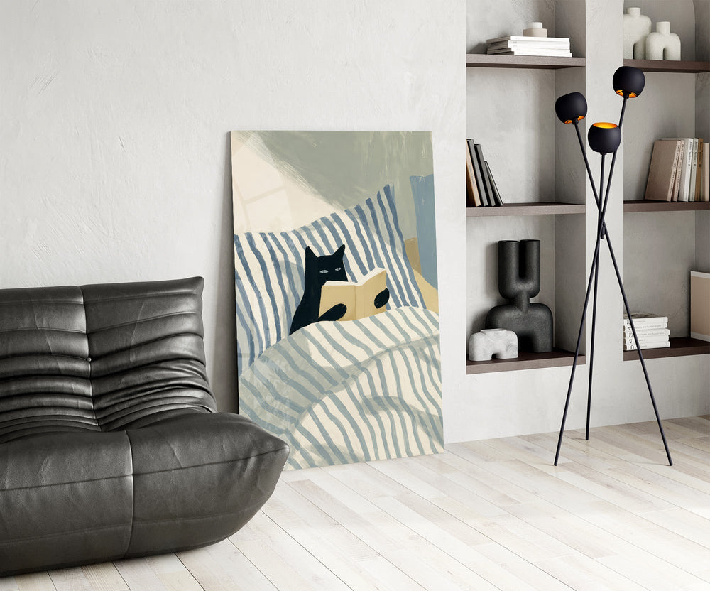 black cat reading in striped bedding glass wall art leaning beside a dark leather sofa