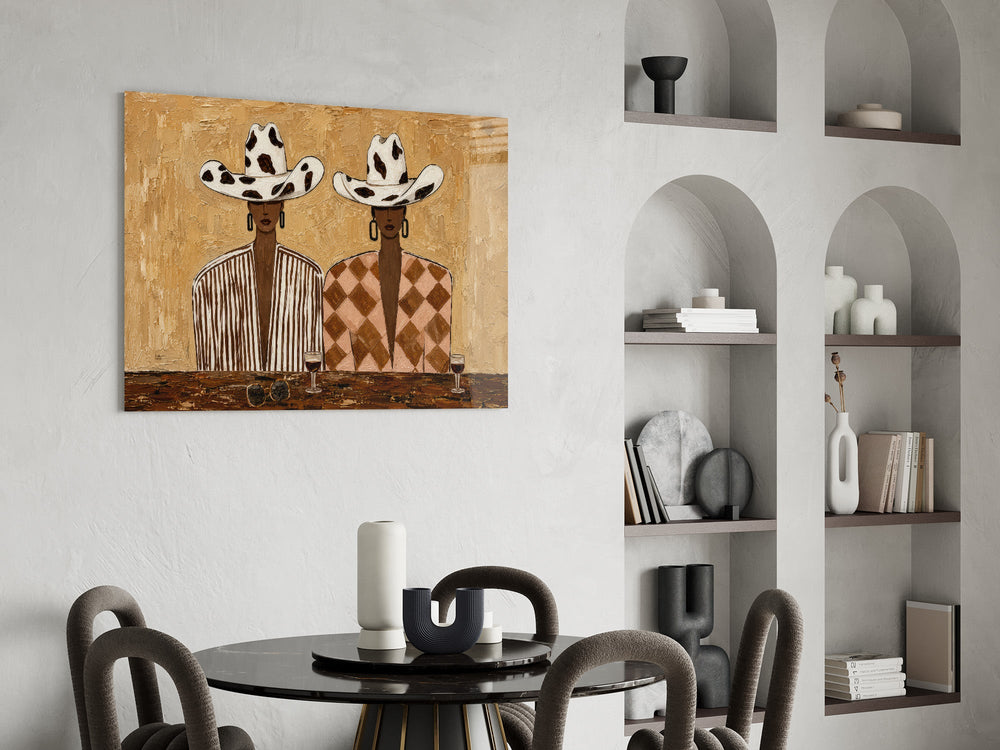 two women in cow-print cowboy hats glass wall art leaning beside a dark leather sofa