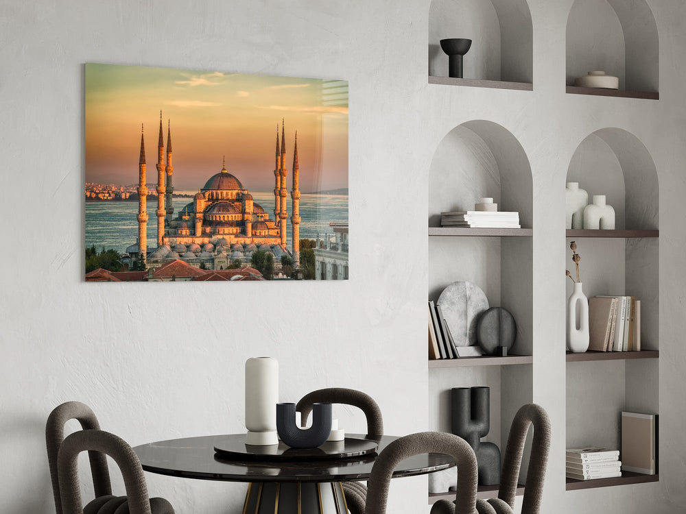 golden sunset six-minaret mosque glass wall art leaning beside a dark leather sofa