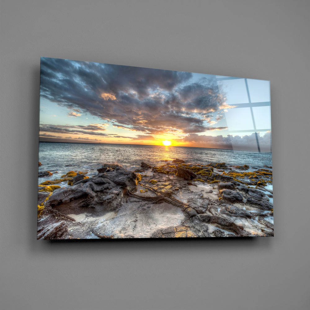 Close-up detail of rocky shoreline meeting dramatic sunset clouds