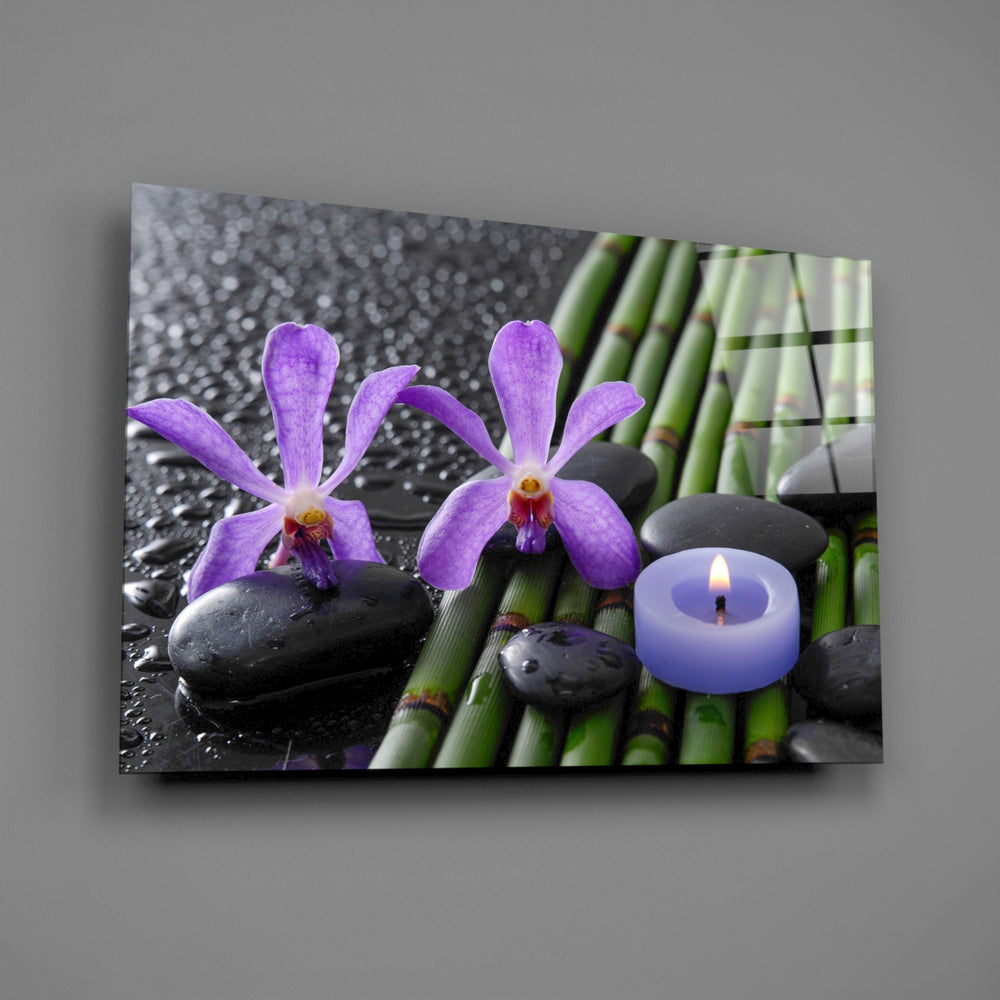 Close-up detail of violet orchids, bamboo, and black spa stones