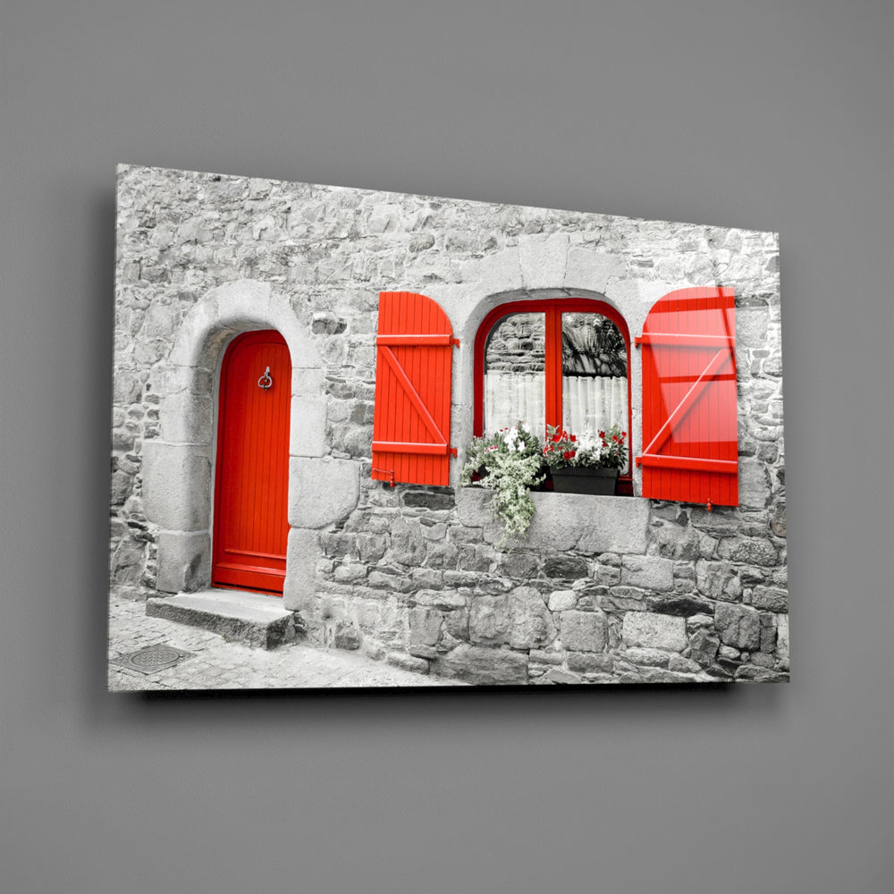 Close-up detail of the red door and shuttered window against gray stone