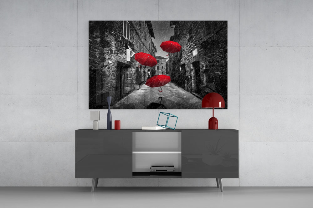 Fine art selective color photography – red umbrellas floating through narrow cobblestone alley flanked by stone buildings in the rain