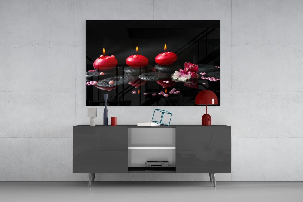 Still life fine art – three red pillar candles glowing on wet black zen stones with pink orchid flower and scattered beads