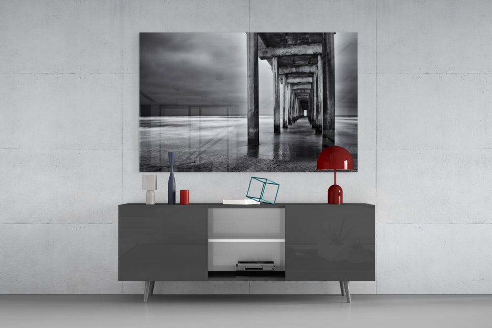 Fine art long exposure photography – beneath a concrete ocean pier at low tide, columns receding symmetrically under overcast sky
